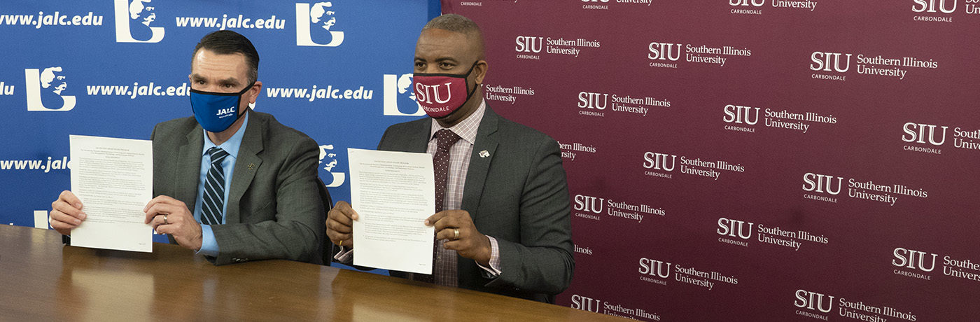 Dr. Kirk Overstreet and Dr. Austin Lane hold up signed papers