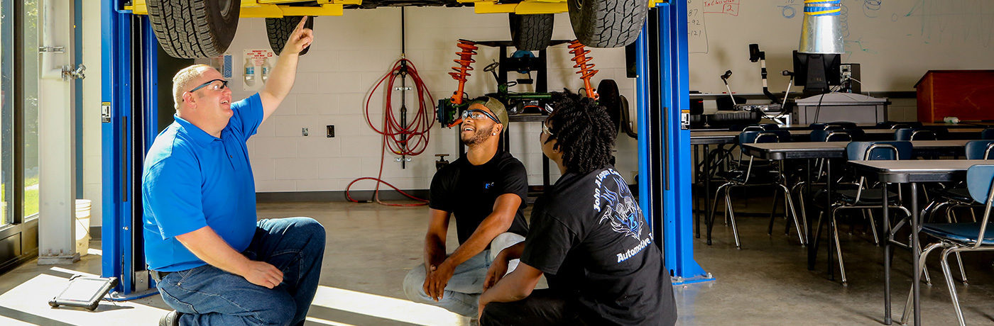 Joseph Roach working with two students on a vehicle