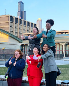 Members of the speech team pose outdoors with thumbs up.