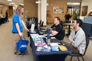 Student gets information from Philip Brewer and Magnus Noble at New Student Orientation Day