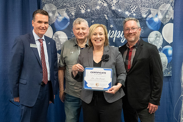 Retiring Professor of Political Science Dr. Jane Bryant with certificate standing next to JALC College President Dr. Kirk Overstreet, board member Jake Rendleman, and Professor of English Matt Garrison.
