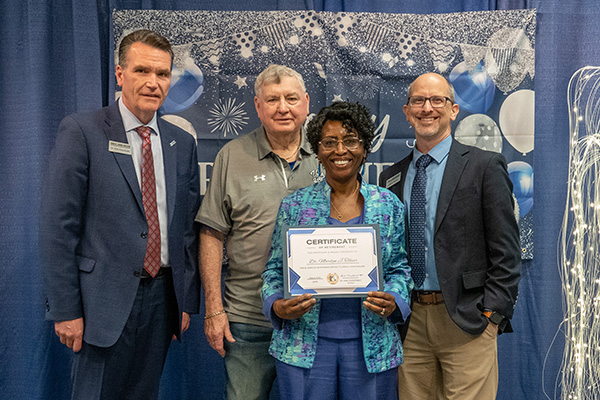 Retiring Professor of Early Childhood Education Dr. Marilyn Toliver with certificate standing next to JALC College President Dr. Kirk Overstreet, board member Jake Rendleman, and Dean of Arts & Sciences Joseph Dethrow.