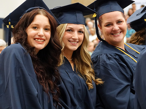 Three students pose together at graduation.