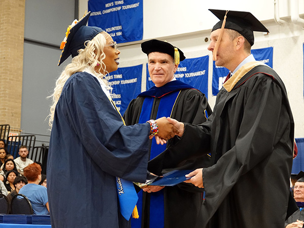Board member Aaron Smith shakes hand of graduating student next to College President Dr. Kirk Overstreet.