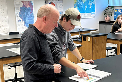 Associate Professor of Electronics Rob Craig looks at course work with student.