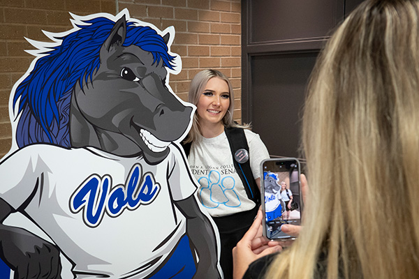 Student gets picture with cutout of JALC mascot Charger.