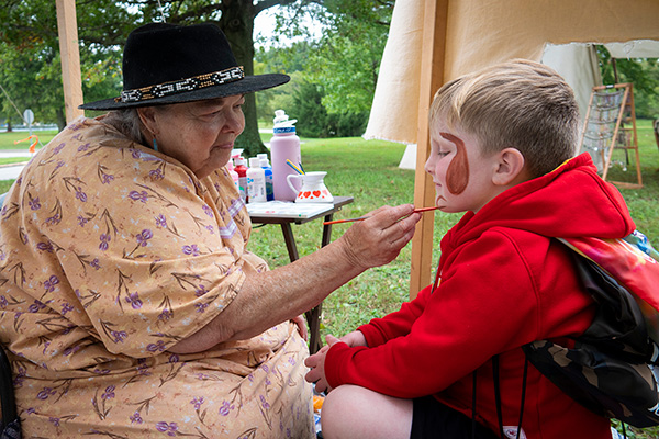 Woman painting child's face at Southern Illinois Hunting and Fishing Days.