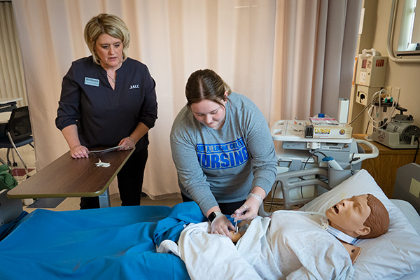 JALC Director of Nursing Dr. Kristin Yosanovich works with student on mannequin patient.