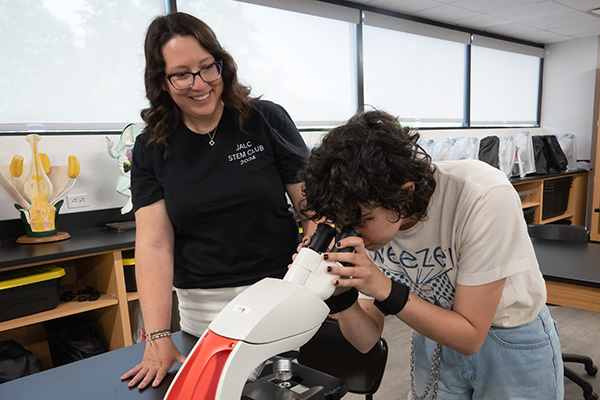 JALC Assistant Professor of Biology, Rebecca Corbit, assists student looking at slide under a microscope.