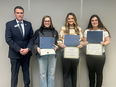 College President Dr. Kirk Overstreet standing with Madison Calvin, Corene Sizemore, and Kassi Teal, who hold their Merit Service Awards.