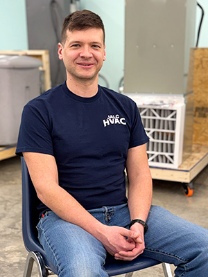 Sean Murphy sitting in chair with HVAC equipment behind him.