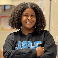 Makayla Collins smiling with arms crossed wearing a JALC sweatshirt.