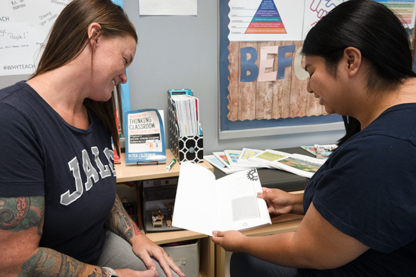 JALC Instructor of Education Erin Sagaskie looks at book with student inside of education classroom at John A. Logan College.